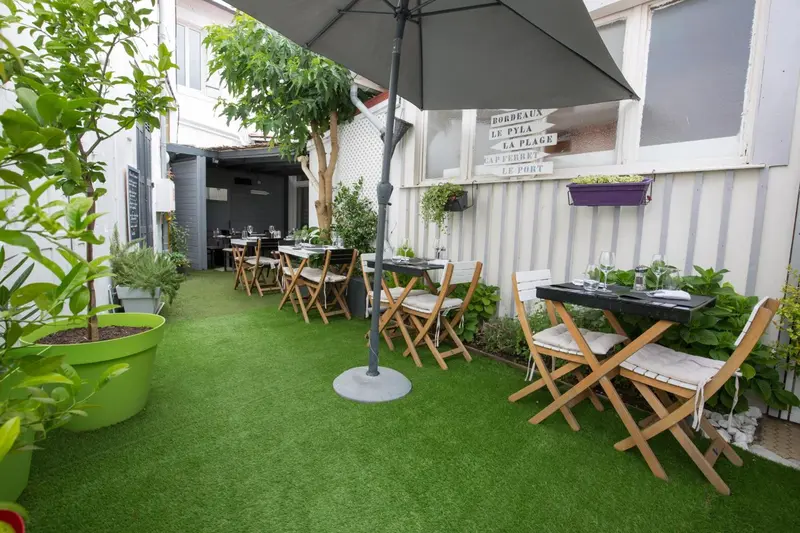 Une terrasse verdoyante avec des tables et des chaises en bois.