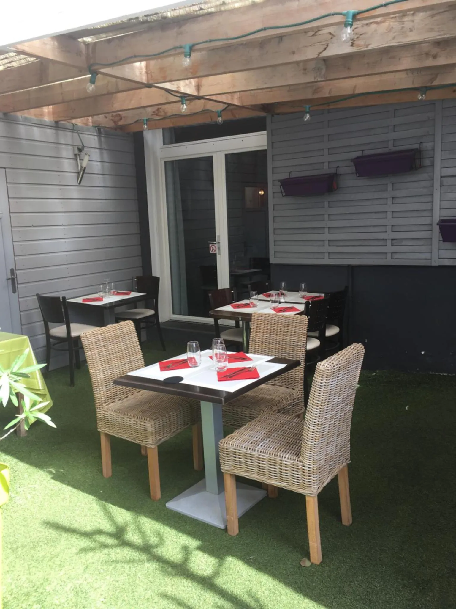 Tables de restaurant dressées sur une terrasse ombragée.
