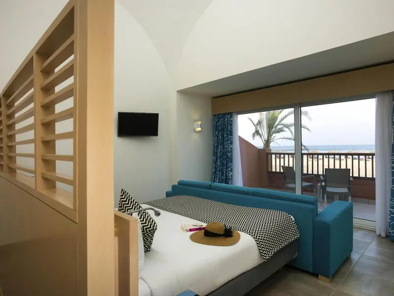 Une chambre lumineuse avec un canapé bleu et un accès à une terrasse vue sur mer.