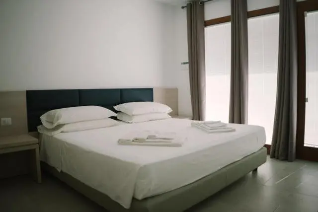 Une chambre lumineuse avec un grand lit recouvert de linge blanc.