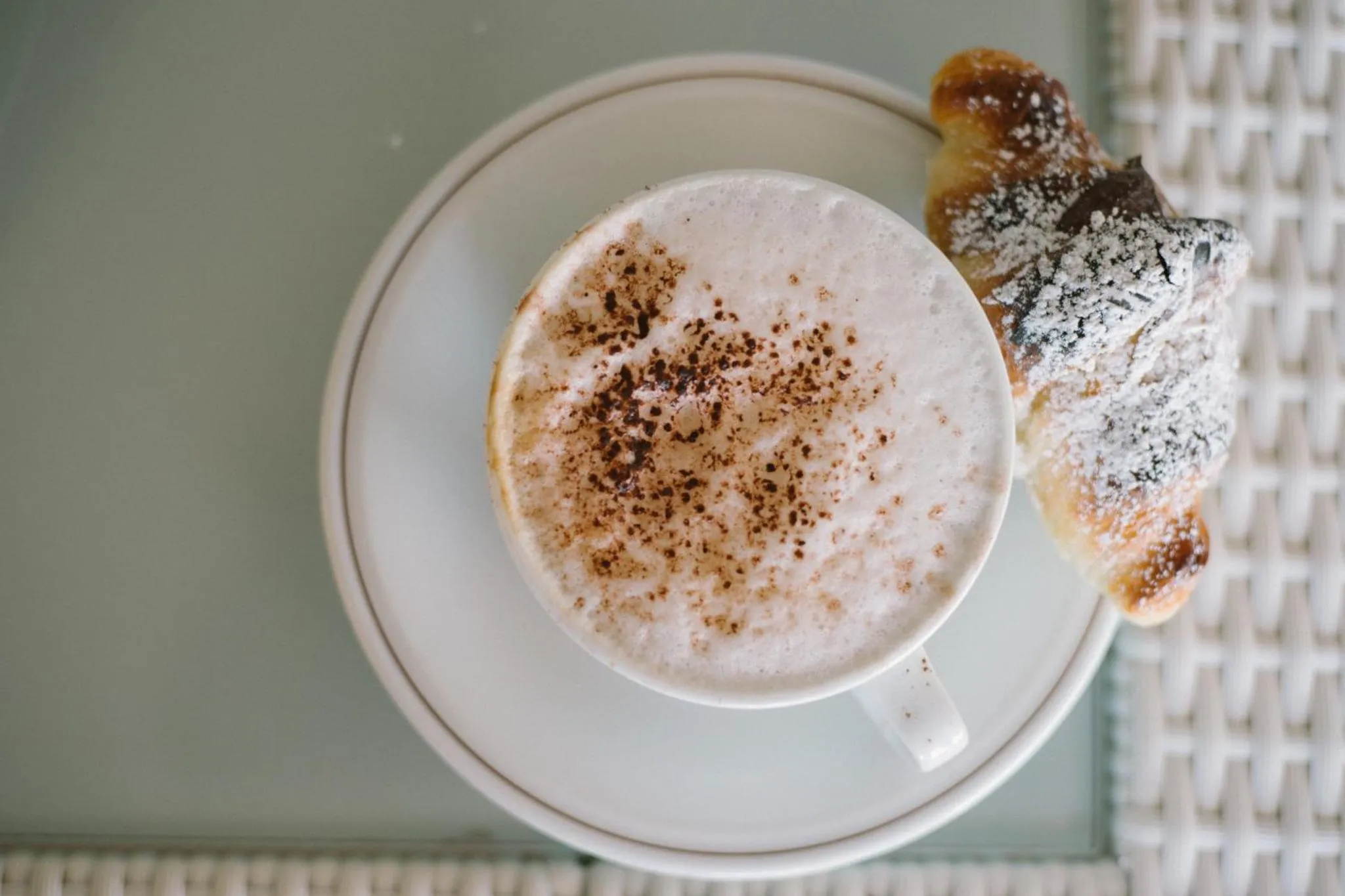 Une tasse de café et une viennoiserie sur une table.