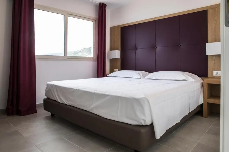 Une chambre lumineuse avec un grand lit recouvert de draps blancs.