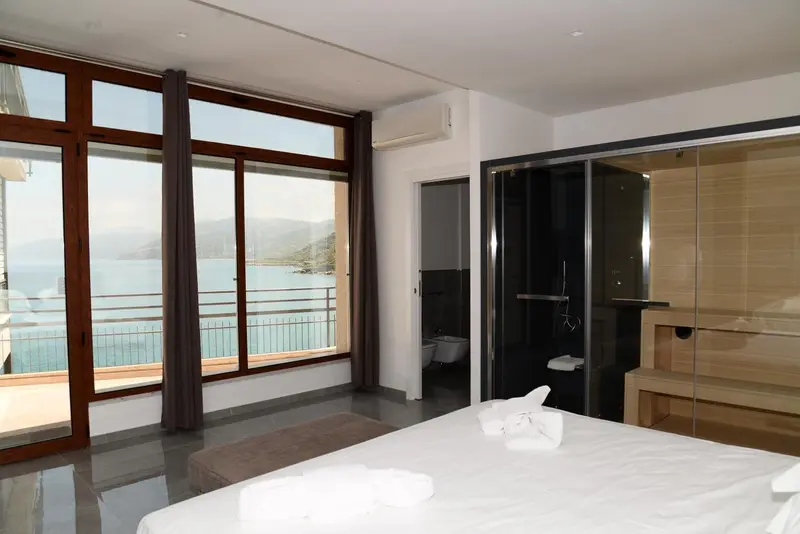 Une chambre lumineuse avec un grand balcon donnant sur la mer.