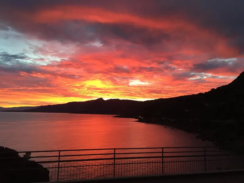 Ciel flamboyant au coucher du soleil sur la mer et les montagnes.