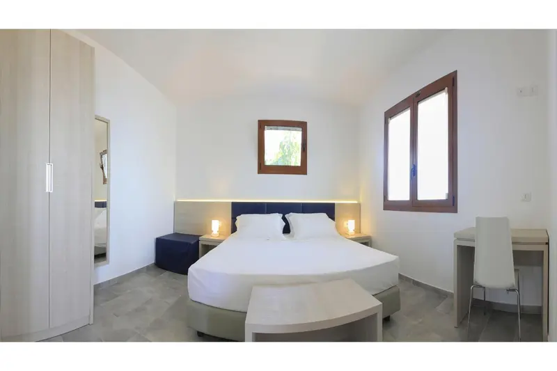Une chambre lumineuse avec un grand lit et un bureau.
