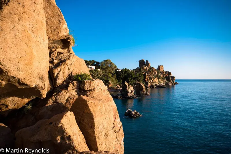 Falaises rocheuses surplombant une mer bleue et des formations côtières.