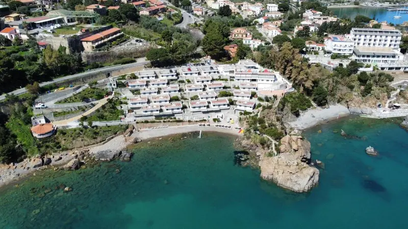Vue aérienne d'un complexe hôtelier en bord de mer avec une plage de galets.
