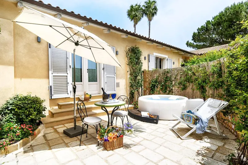 Une terrasse pavée avec un jacuzzi et un coin repas ensoleillé.