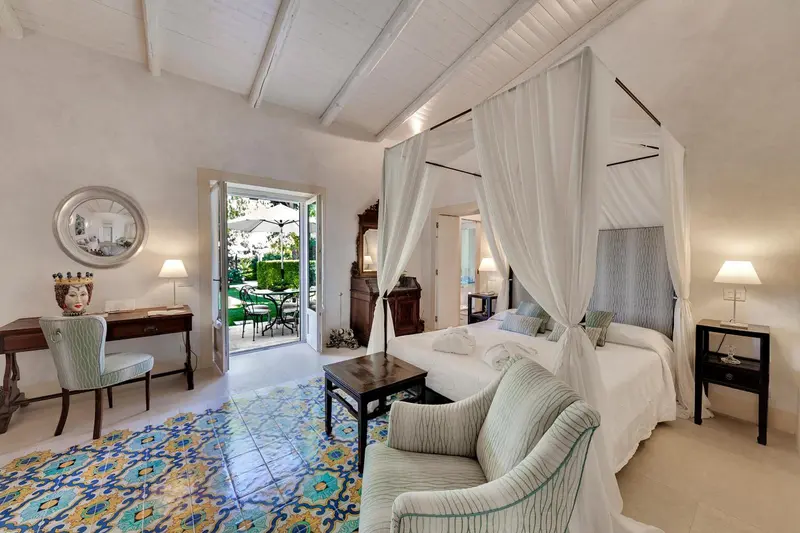 Une chambre lumineuse avec un lit à baldaquin et un coin salon.