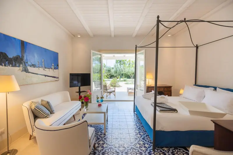 Une chambre lumineuse avec un lit à baldaquin et un canapé face à une ouverture sur l'extérieur.