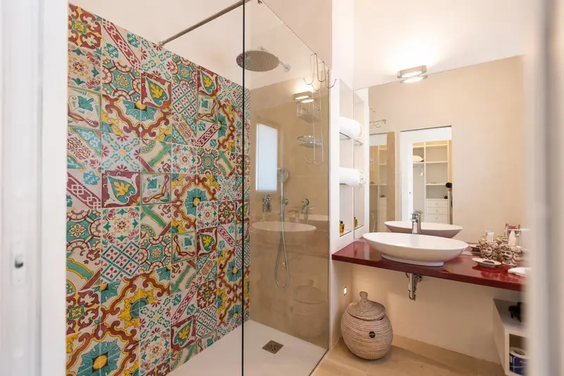 Une salle de bain lumineuse avec une douche à l'italienne aux motifs colorés.