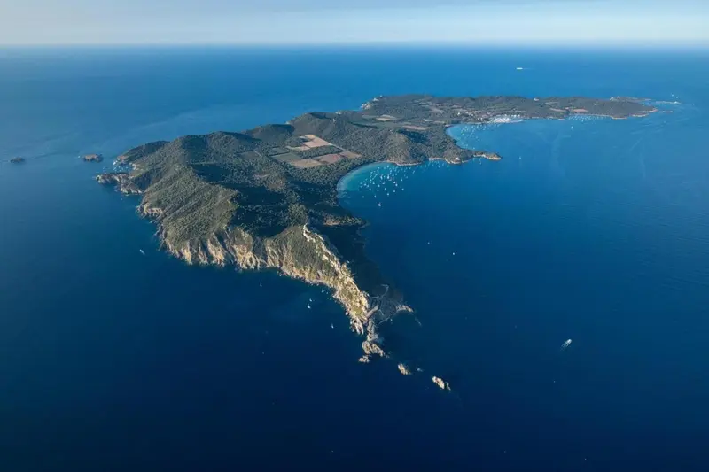 Vue aérienne d'une île rocheuse entourée d'eaux bleues.