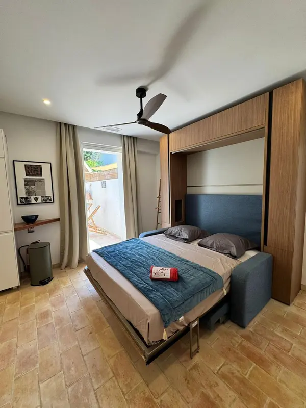 Une chambre avec un lit escamotable et une vue sur une terrasse.