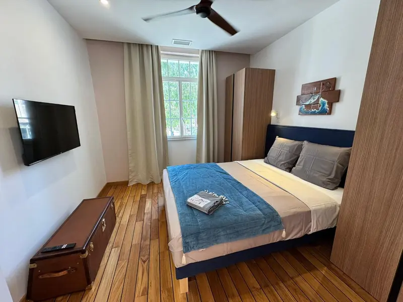 Une chambre lumineuse avec un lit double et une télévision murale.