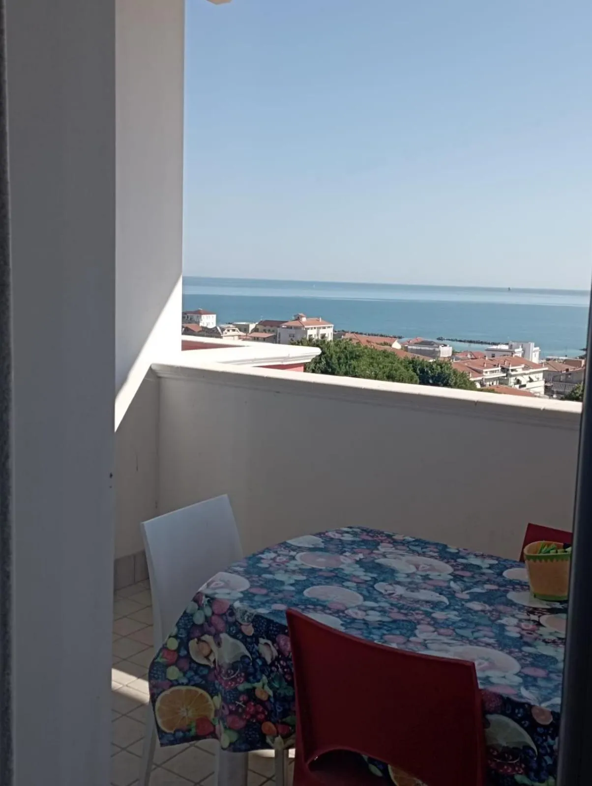 Une table et des chaises se trouvent sur un balcon avec vue sur la mer et la ville.