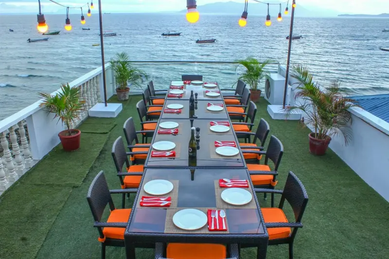 Une longue table est dressée pour un repas en extérieur avec vue sur la mer.