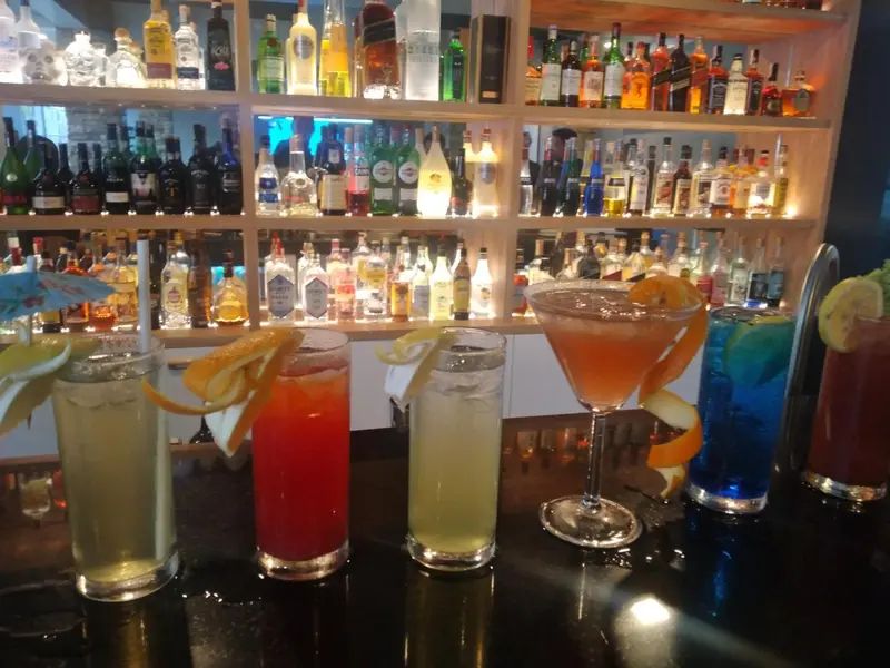 Des cocktails colorés sont présentés sur un comptoir de bar éclairé.