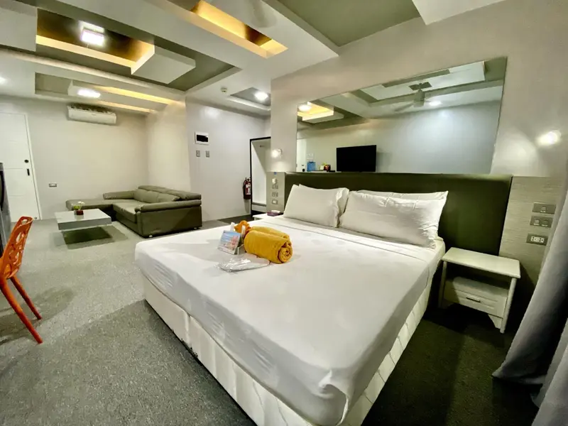 Une chambre lumineuse avec un grand lit et un coin salon.