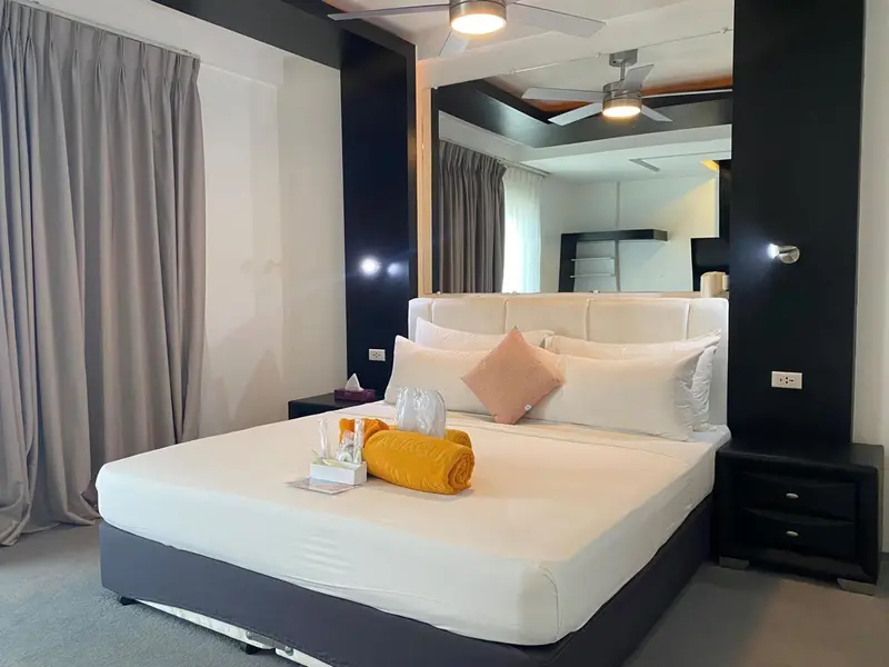 Une chambre lumineuse avec un grand lit recouvert de linge blanc et de coussins.