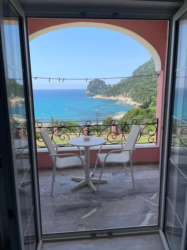Une terrasse avec table et chaises offre une vue sur la mer et les montagnes.