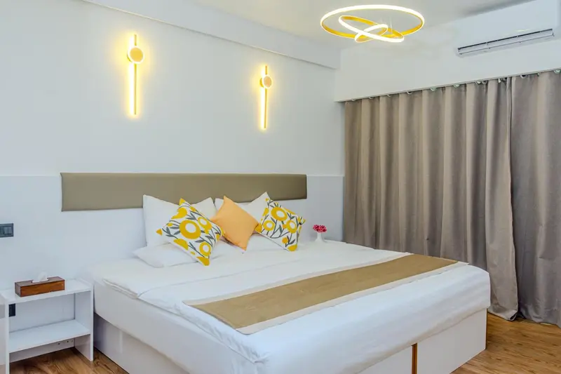 Une chambre lumineuse avec un grand lit recouvert d'une courtepointe et de coussins.