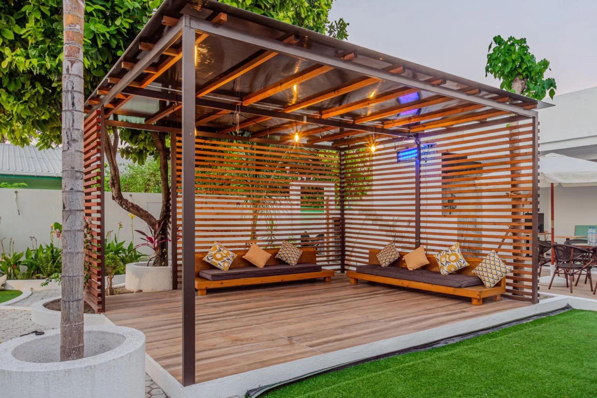 Espace de détente extérieur avec des coussins sur des bancs en bois.