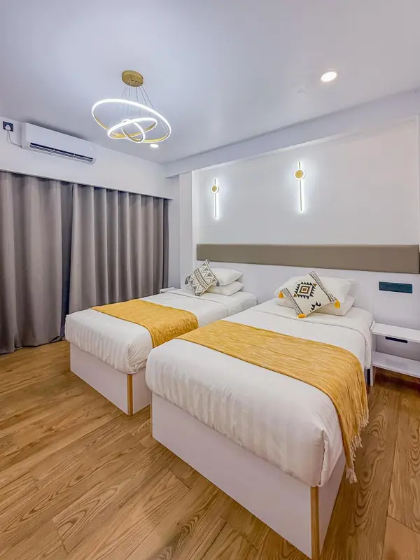 Une chambre lumineuse avec deux lits simples et une décoration moderne.