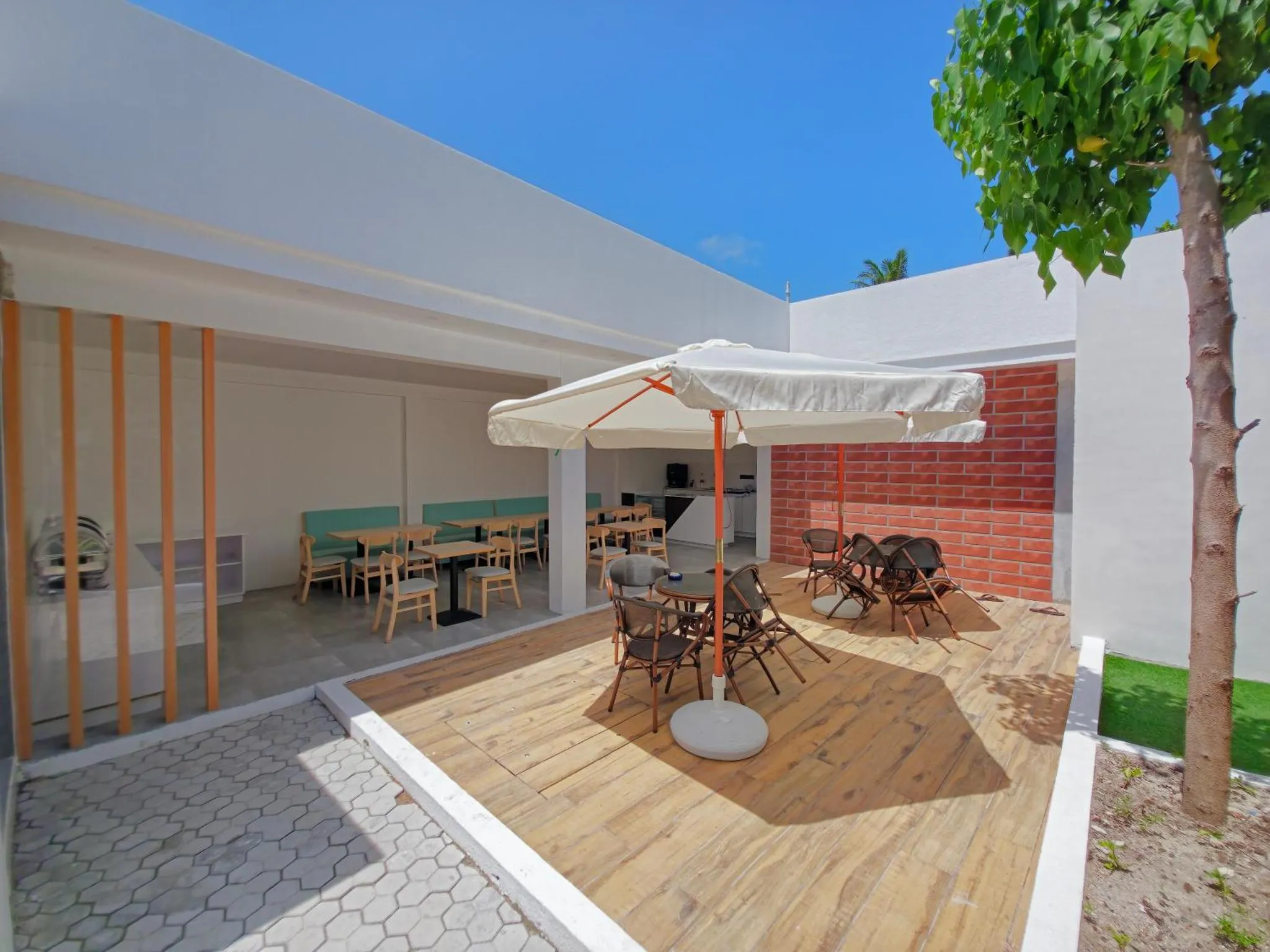 Terrasse ombragée avec tables et chaises en bois.