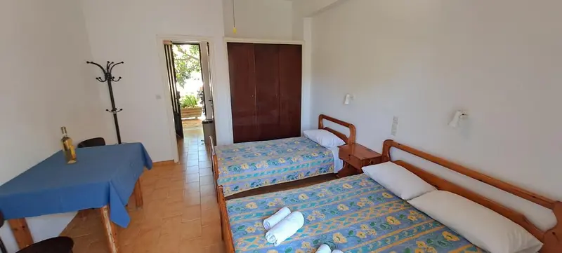 Une chambre lumineuse avec deux lits simples et un coin repas.