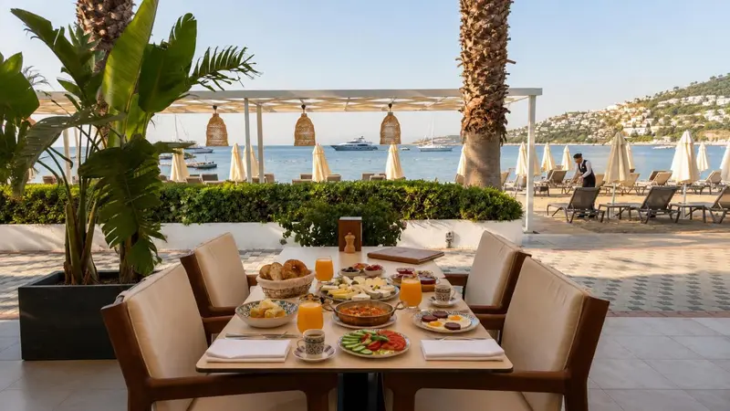 Une table est dressée pour le petit-déjeuner avec vue sur la mer et les bateaux.