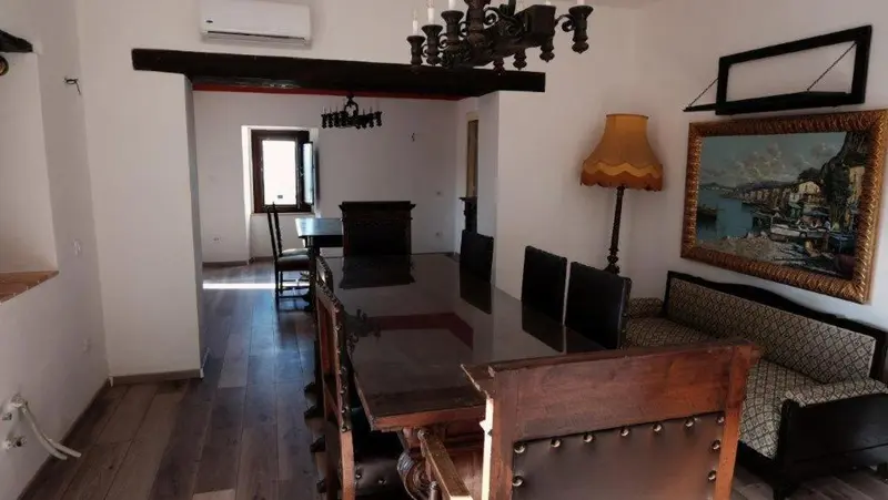 Une salle à manger lumineuse avec une grande table en bois et un canapé.