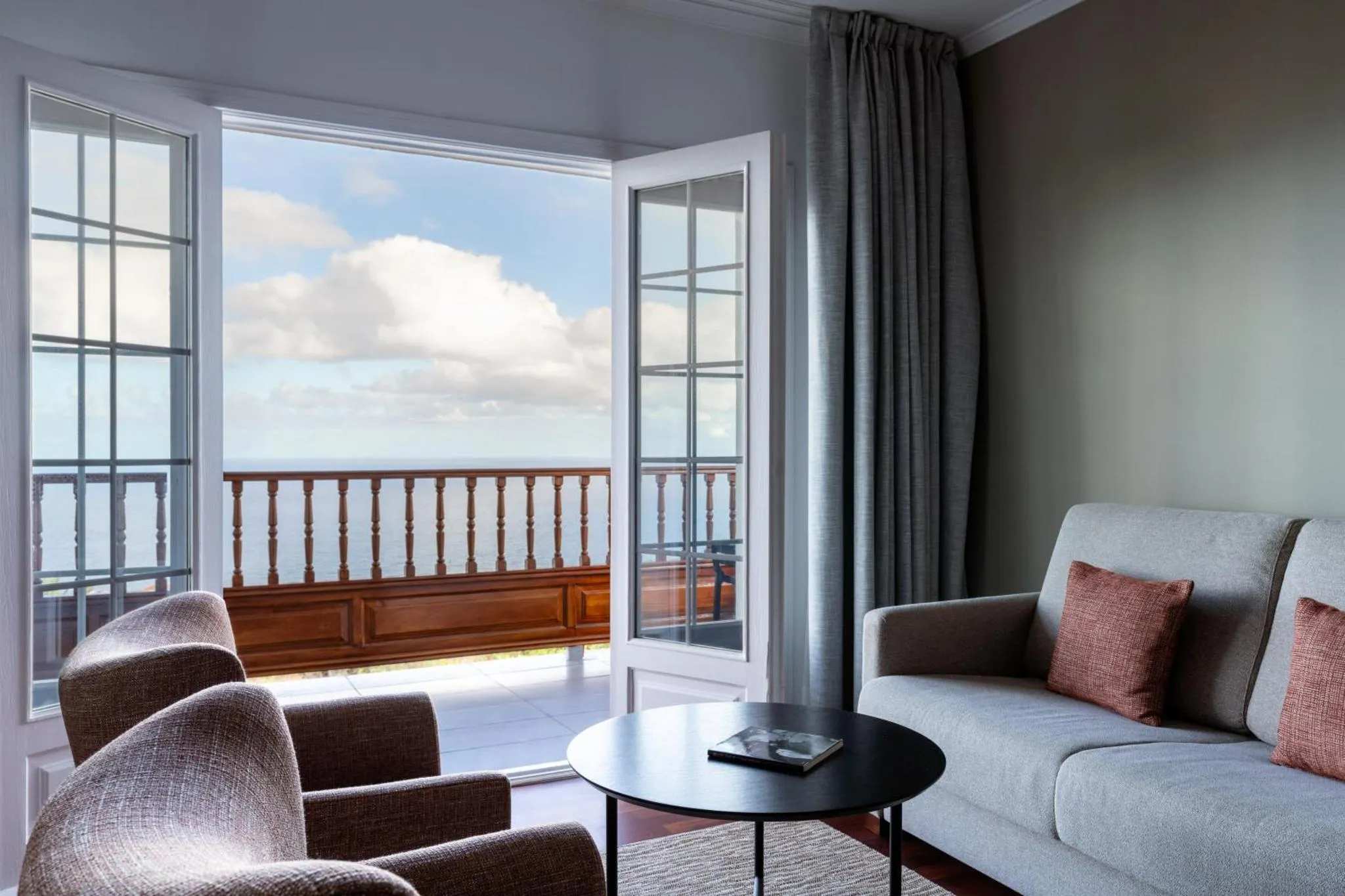 Espace de détente lumineux avec canapés et vue sur la mer.