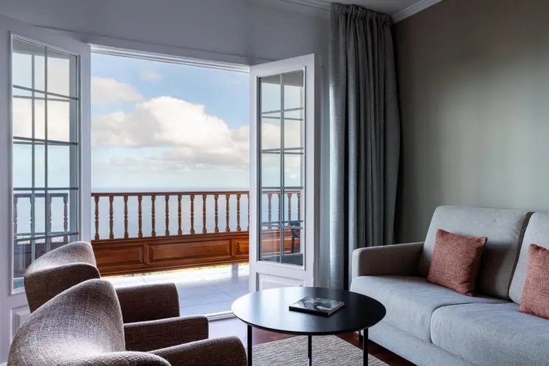 Espace de détente lumineux avec canapés et vue sur la mer.