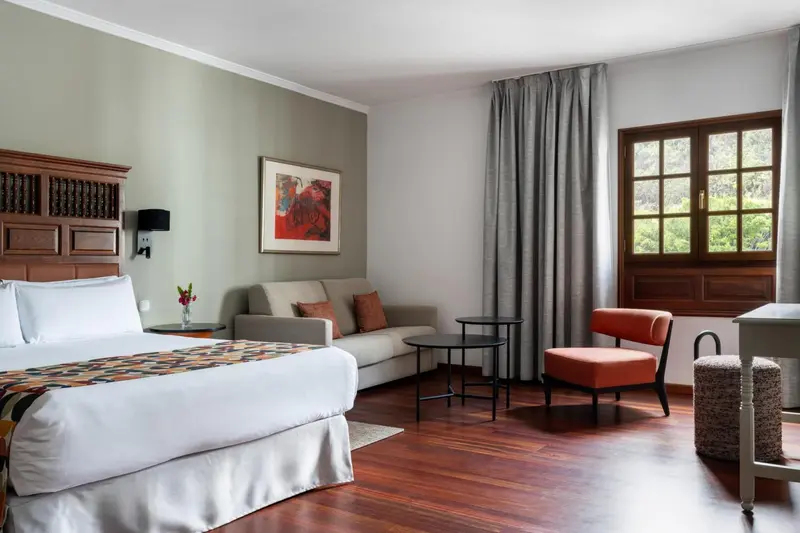 Une chambre lumineuse avec un lit, un canapé et un fauteuil.