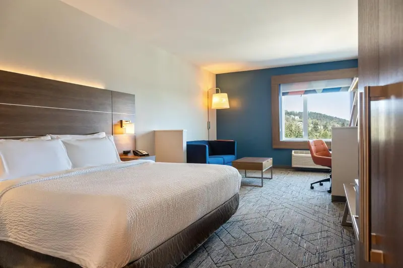 Une chambre lumineuse avec un grand lit et un coin salon près d'une fenêtre.