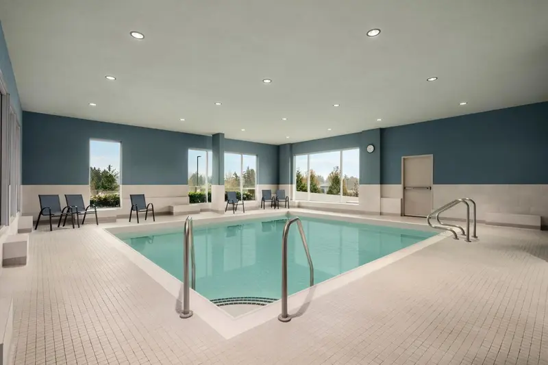 Une piscine intérieure lumineuse avec des chaises longues sur le bord.