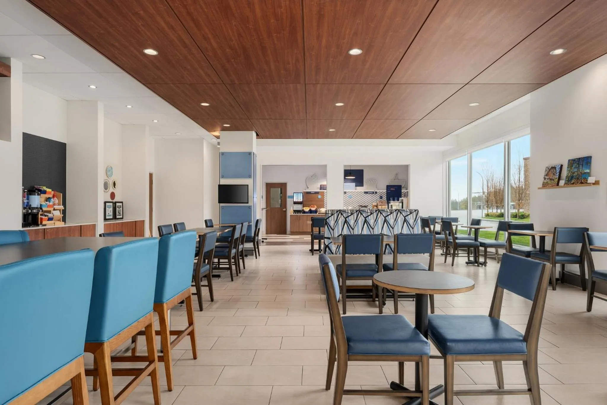 Une salle lumineuse avec des tables et des chaises, un comptoir de bar et une fenêtre.