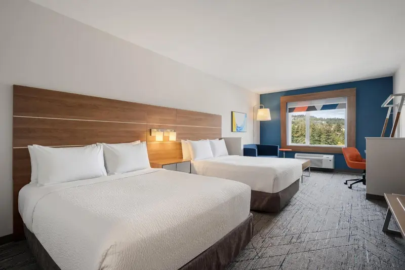 Chambre lumineuse avec deux lits et une fenêtre donnant sur un paysage.