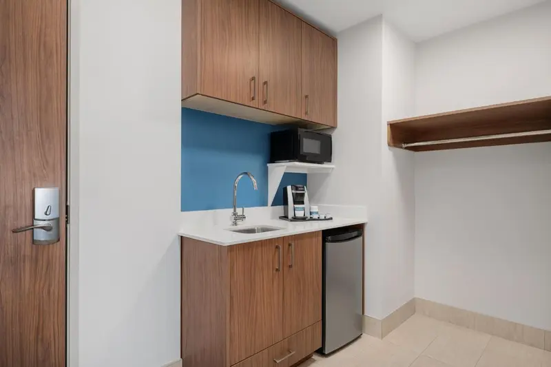 Une kitchenette moderne avec un évier, un micro-ondes et un réfrigérateur.