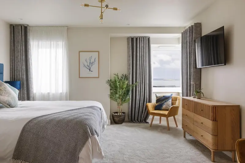 Une chambre lumineuse avec un grand lit et un coin salon près d'une fenêtre.