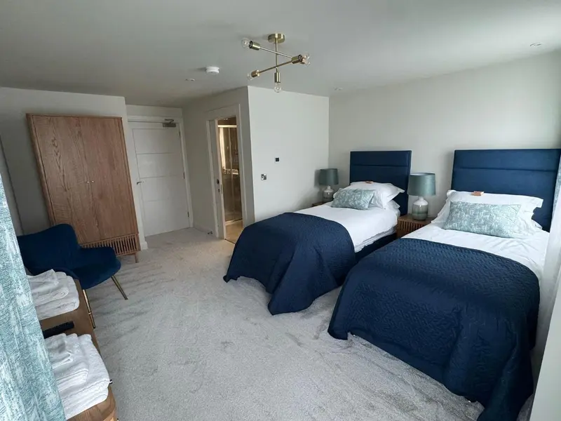 Une chambre avec deux lits simples et un fauteuil bleu.