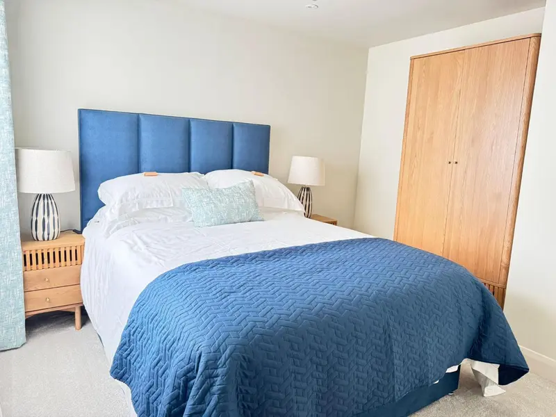 Une chambre lumineuse avec un grand lit recouvert d'une courtepointe bleue.