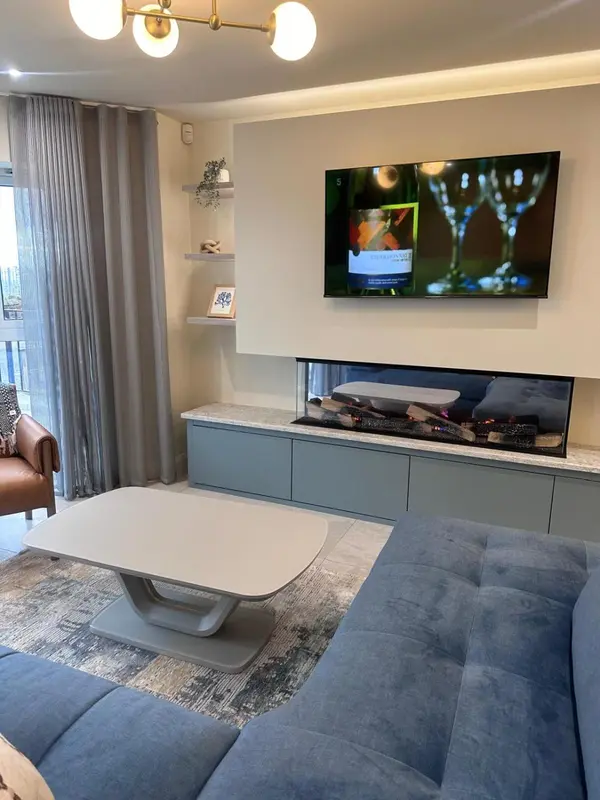 Un salon moderne avec un canapé, une table basse et une cheminée électrique.