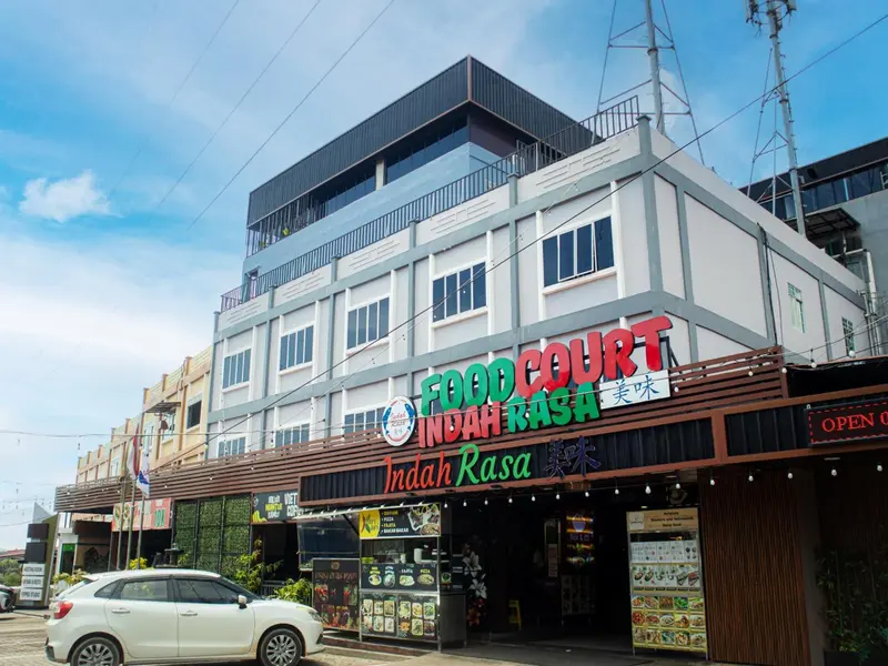 Façade d'un bâtiment moderne avec une devanture de restaurant et un parking.