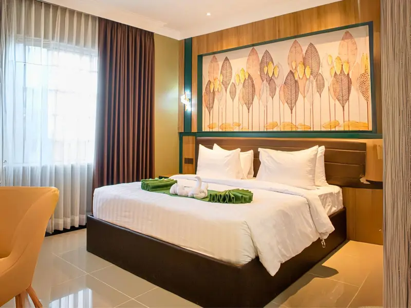 Une chambre lumineuse avec un grand lit recouvert d'une courtepointe blanche et de décorations en forme de cygnes.