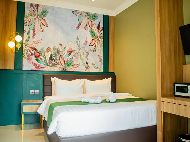 Une chambre d'hotel avec un grand lit recouvert d'une couette blanche et de coussins.