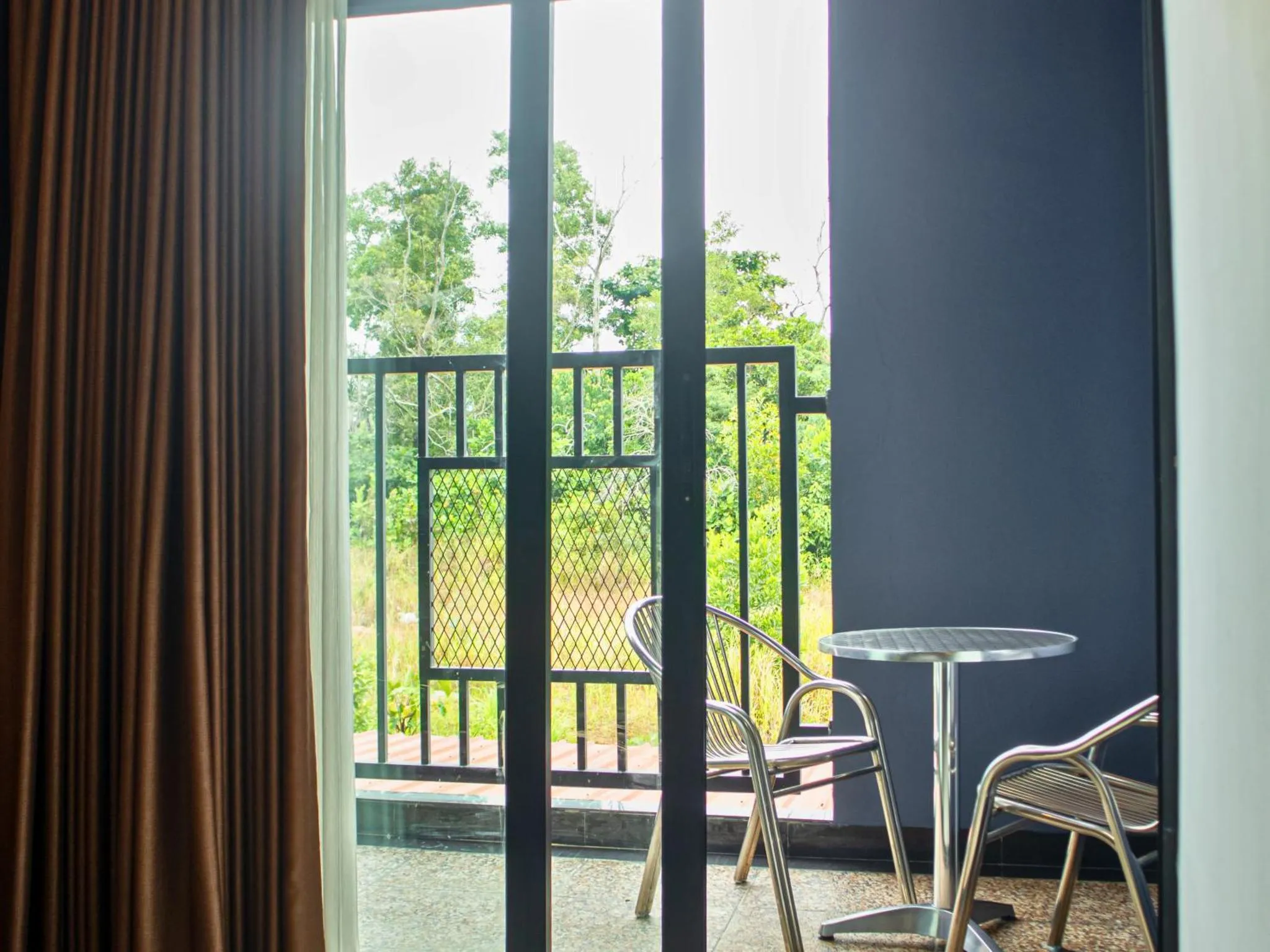Une terrasse avec une table et des chaises offre une vue sur la végétation.