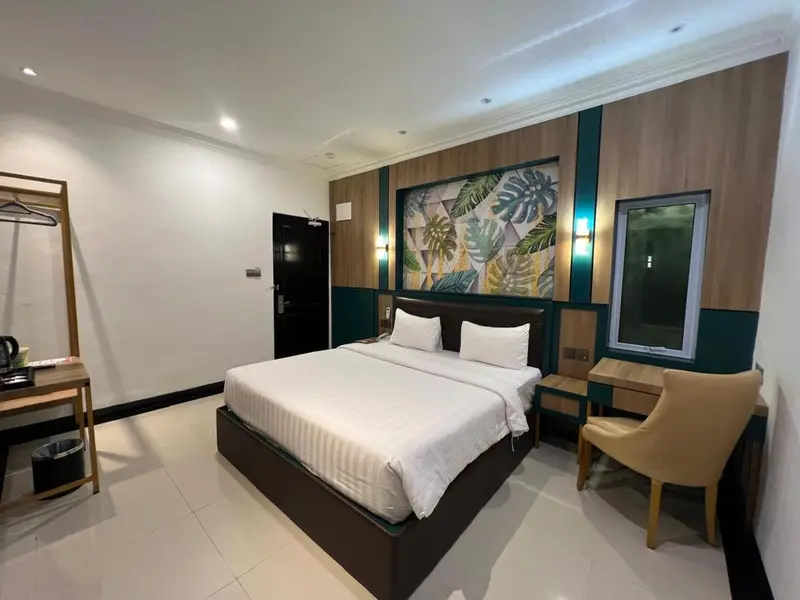 Une chambre lumineuse avec un grand lit recouvert d'une courtepointe blanche et d'oreillers.