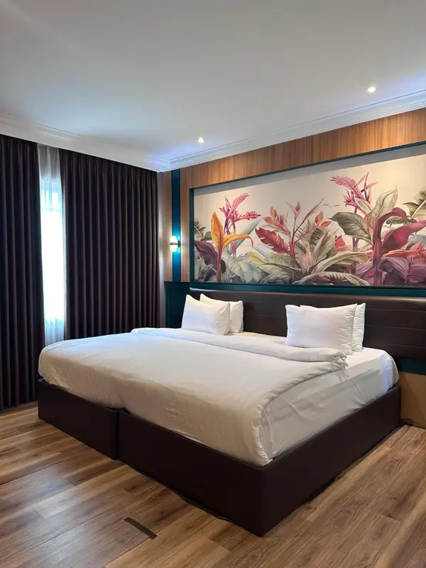 Une chambre avec un grand lit recouvert de draps blancs et une décoration florale murale.