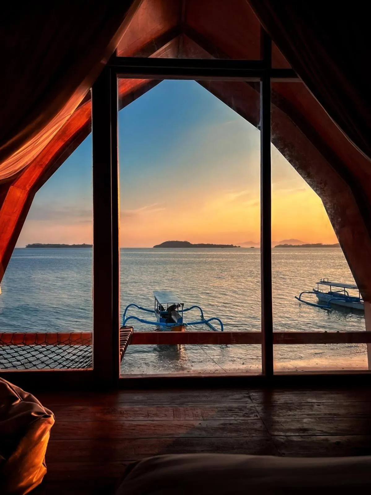 Vue sur la mer et le coucher de soleil à travers une fenêtre.